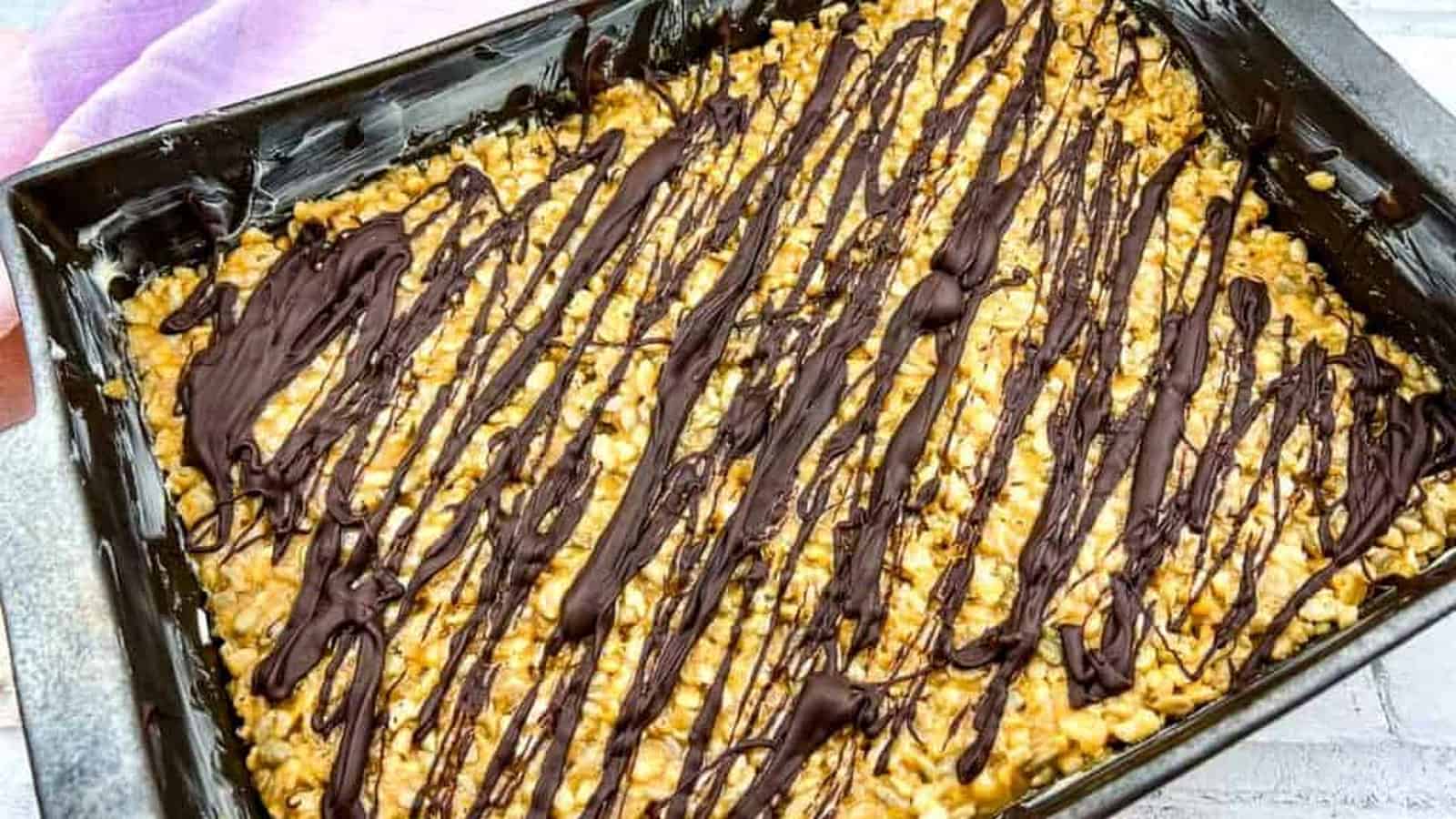 A rectangular baking pan filled with molly bars and melted chocolate drizzle.