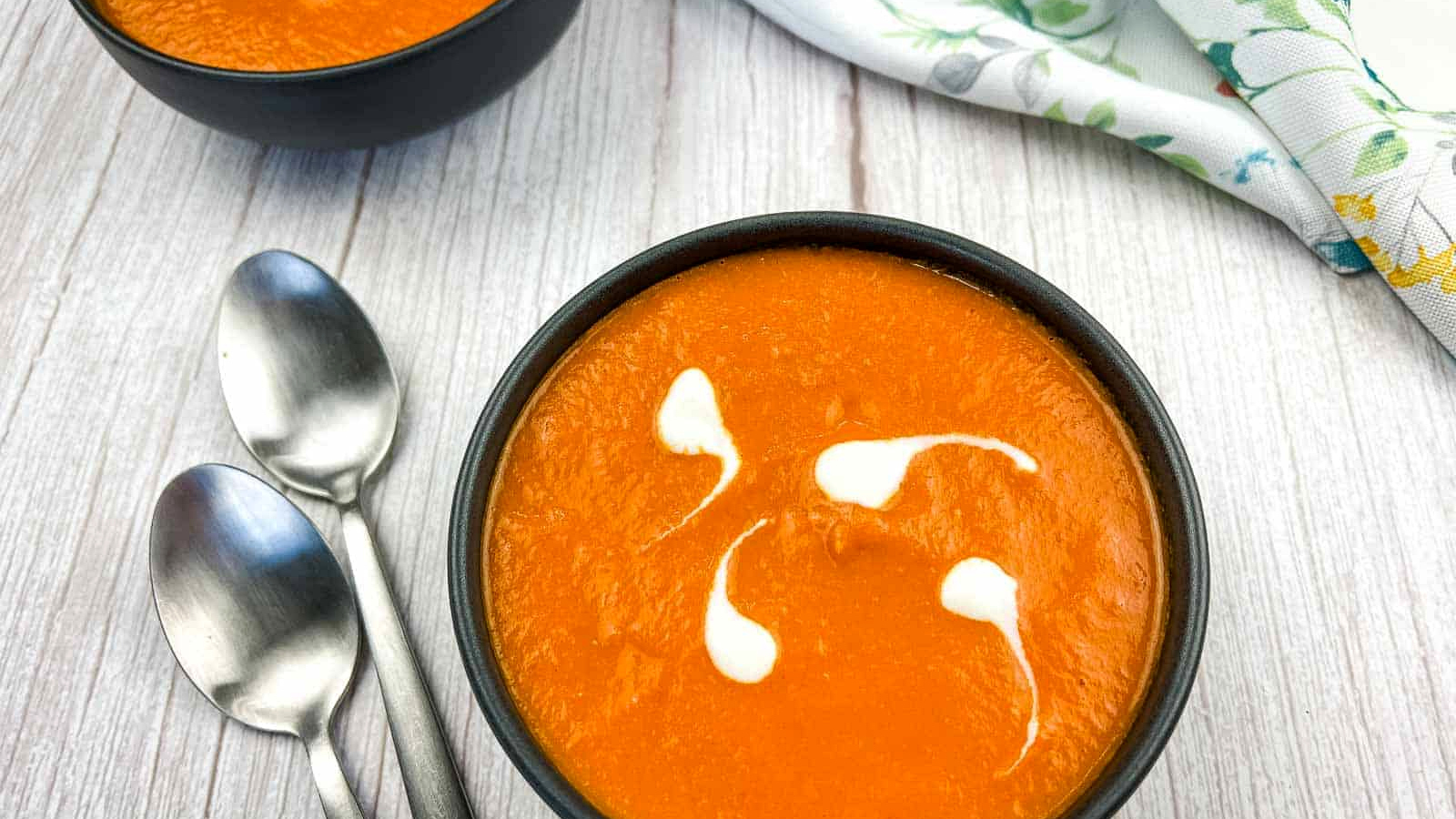 A bowl of oven-roasted tomato soup with two spoons.