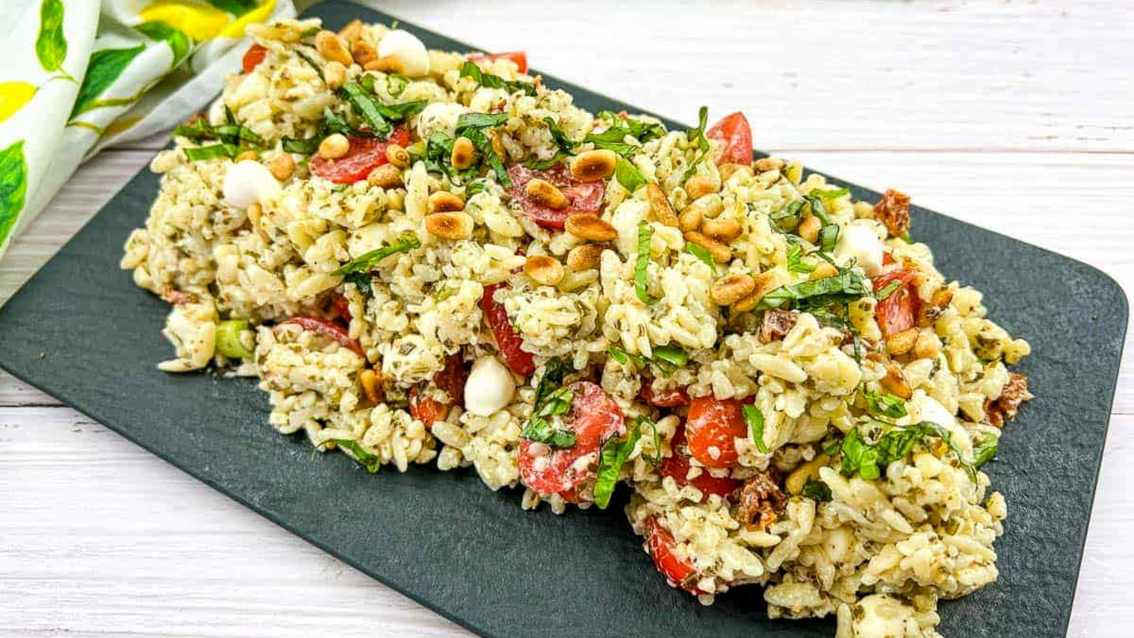 Orzo salad resting on a dark plate.
