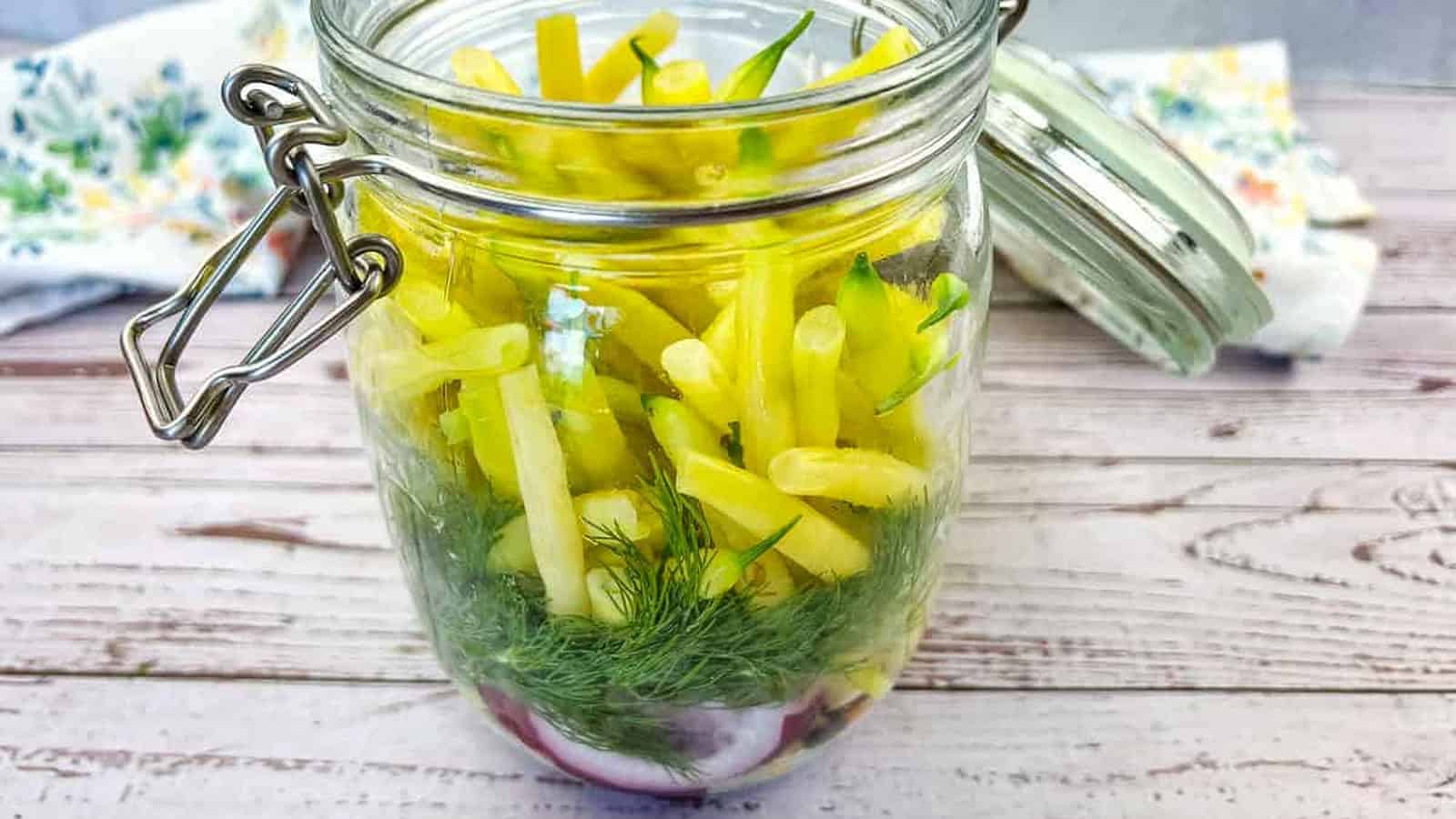 Pickled yellow beans in a jar on a wooden table.