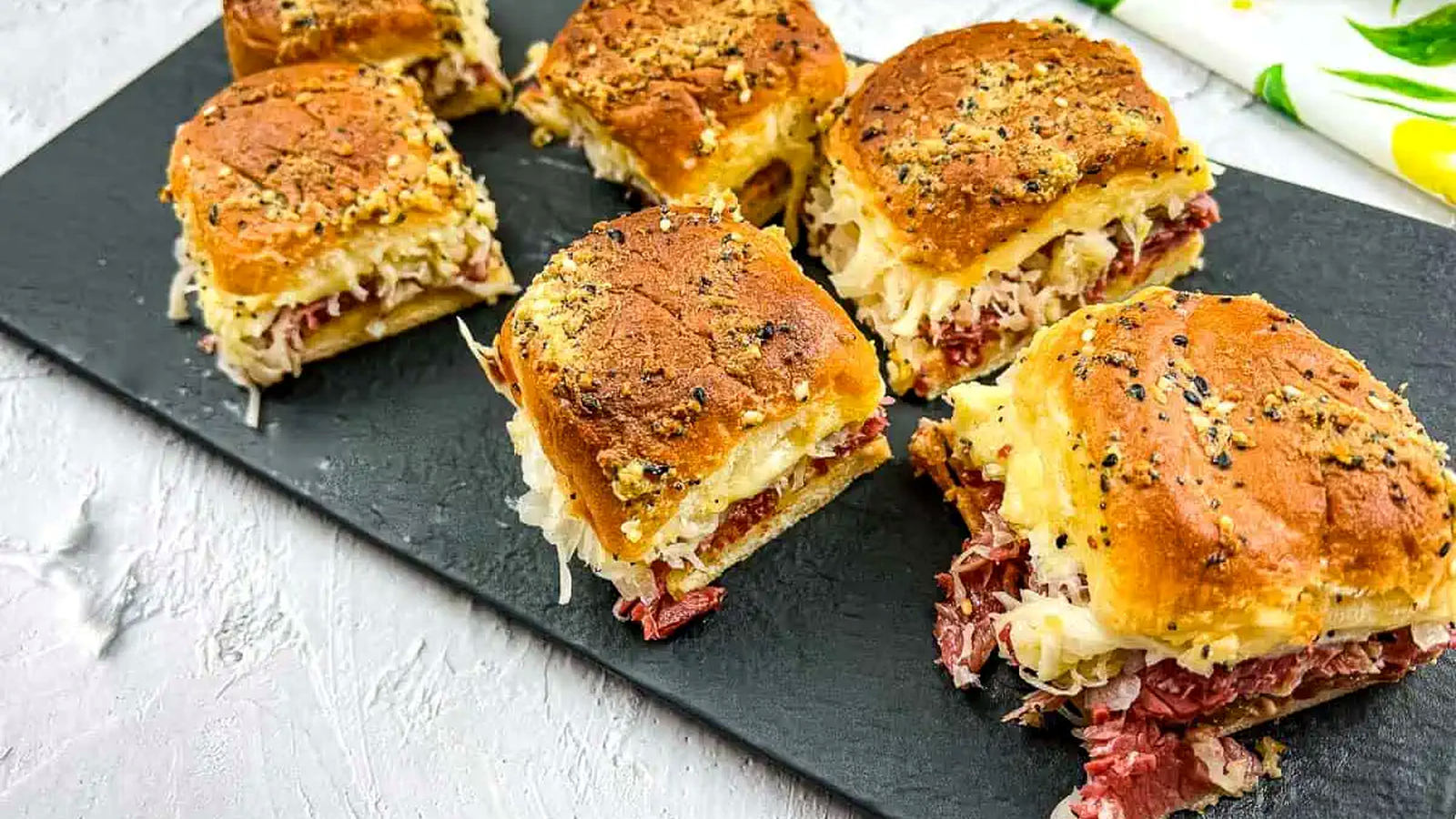 Reuben sliders on a slate board.