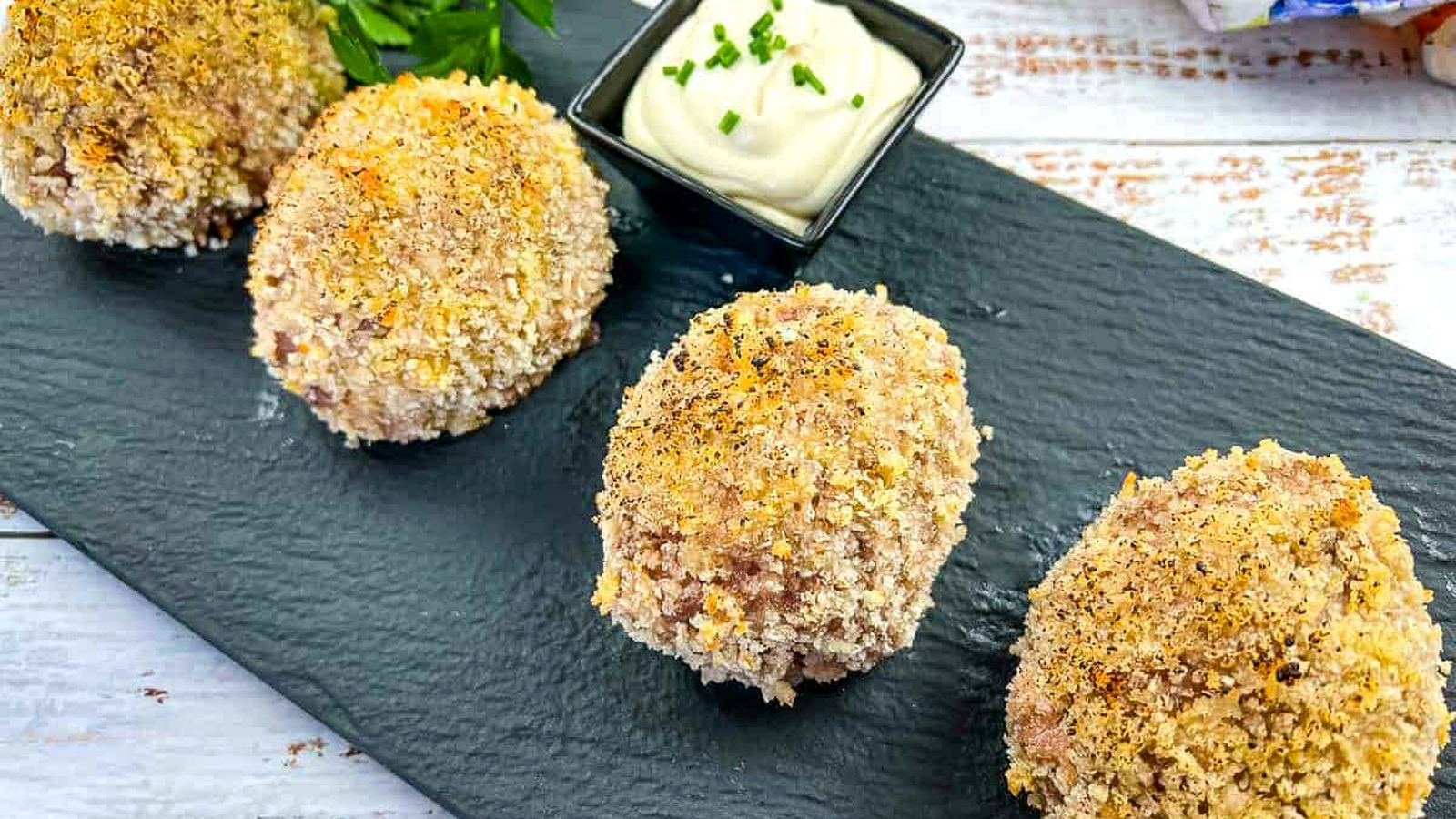 Scotch Eggs on a black plate.