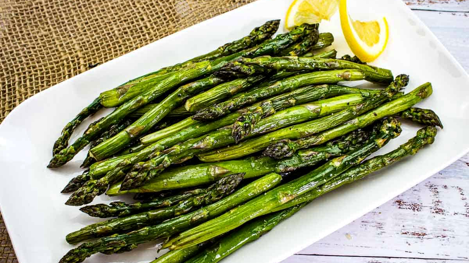 Smoked asparagus on a white platter with lemon.