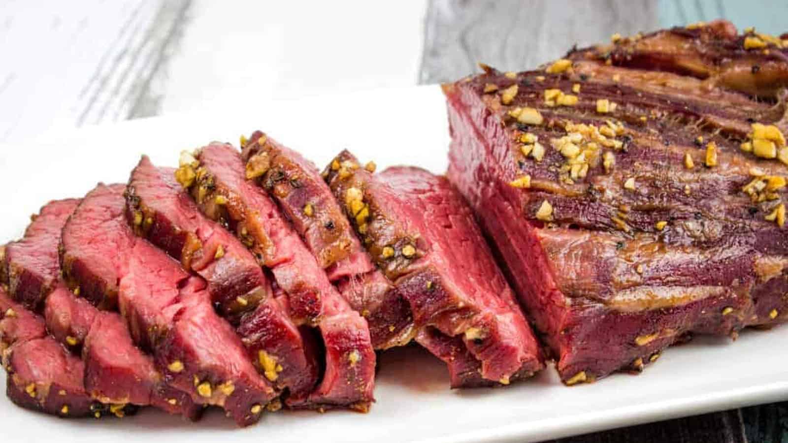 A sliced smoked beef tenderloin on a white plate.