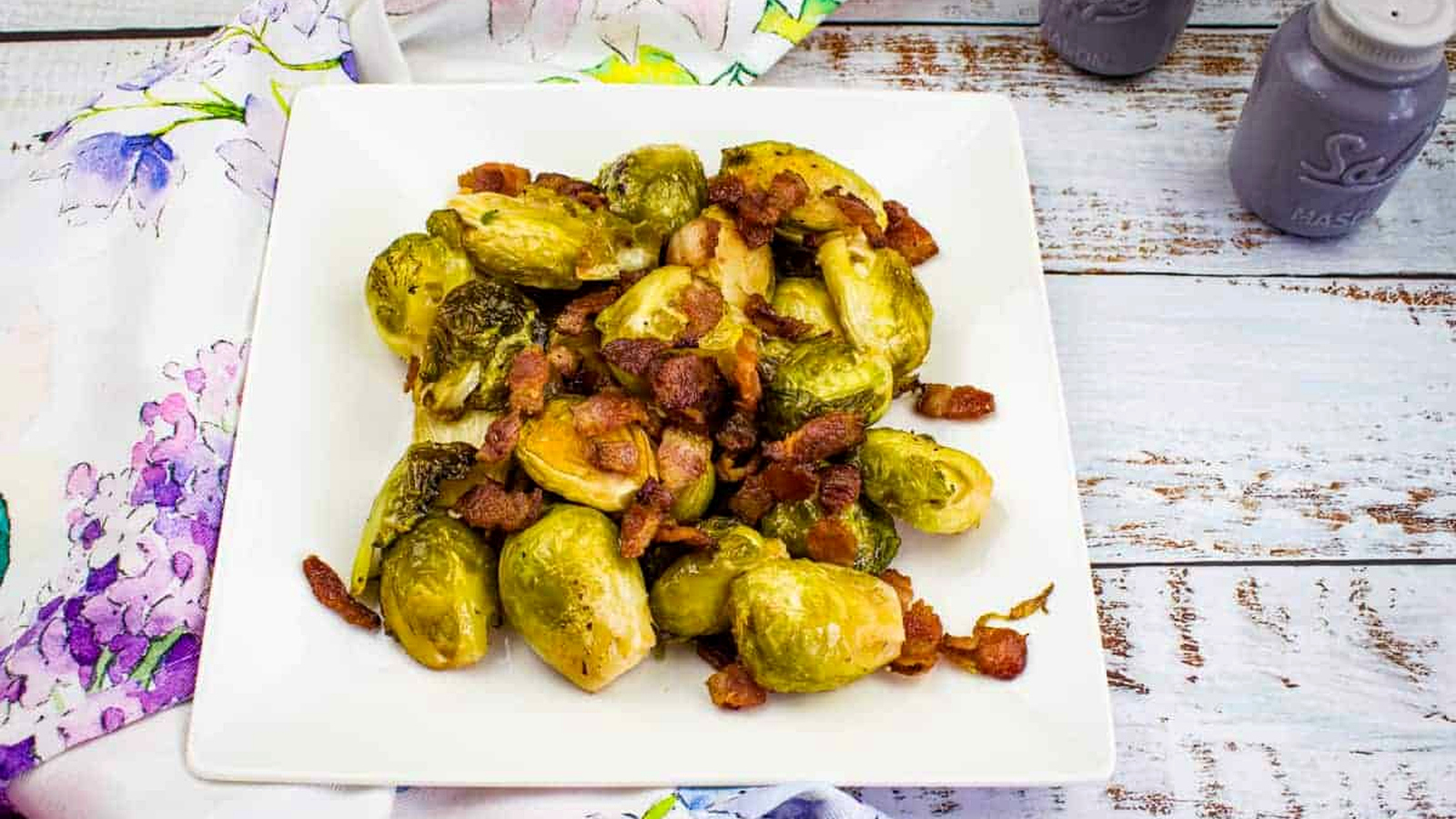 Smoked Brussels Sprouts with bacon on a white plate.