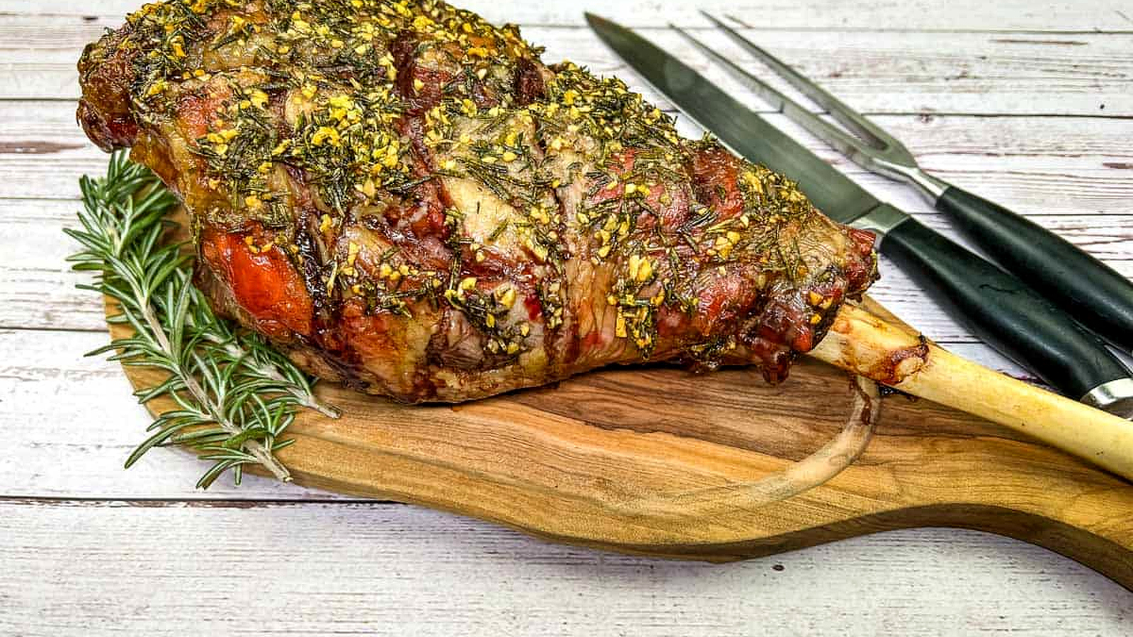 Whole cooked leg of lamb on a board with a knife.