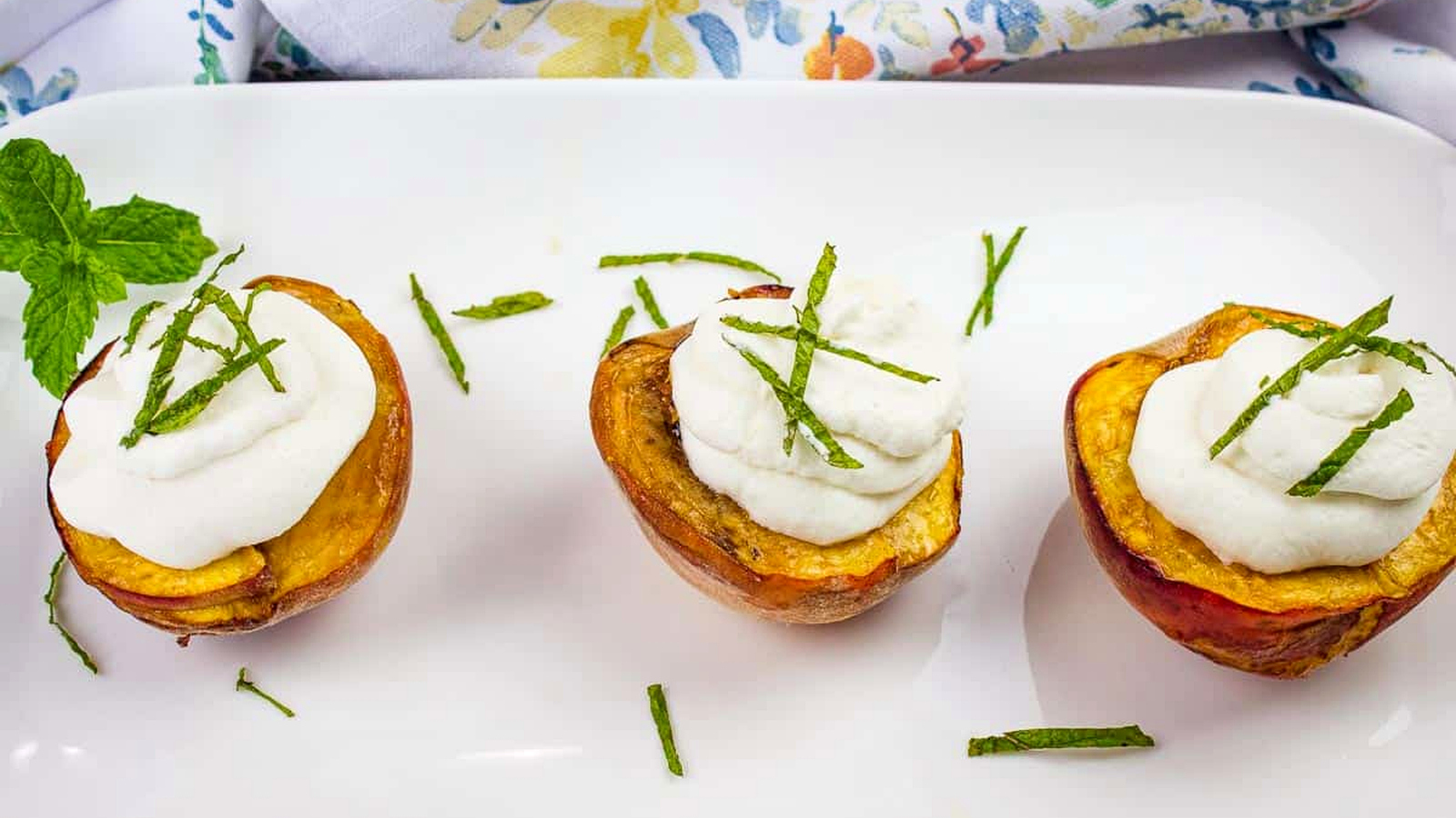 Smoked peaches topped with spiced rum whipped cream on a platter.