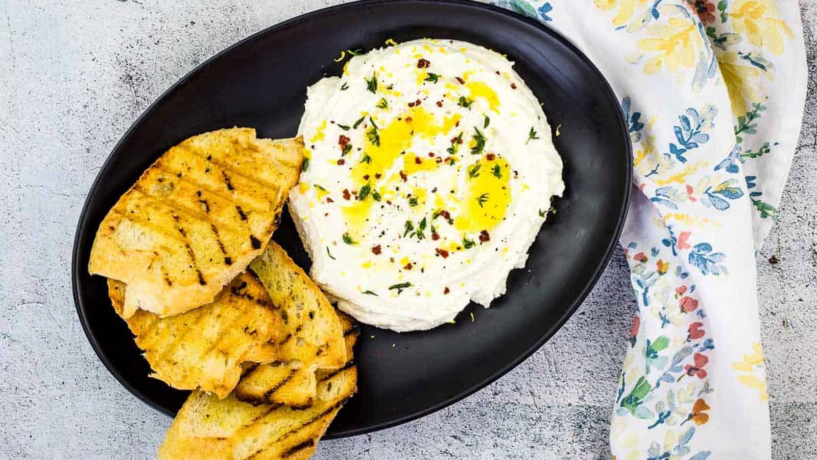 Whipped Feta on a black plate with grilled bread.