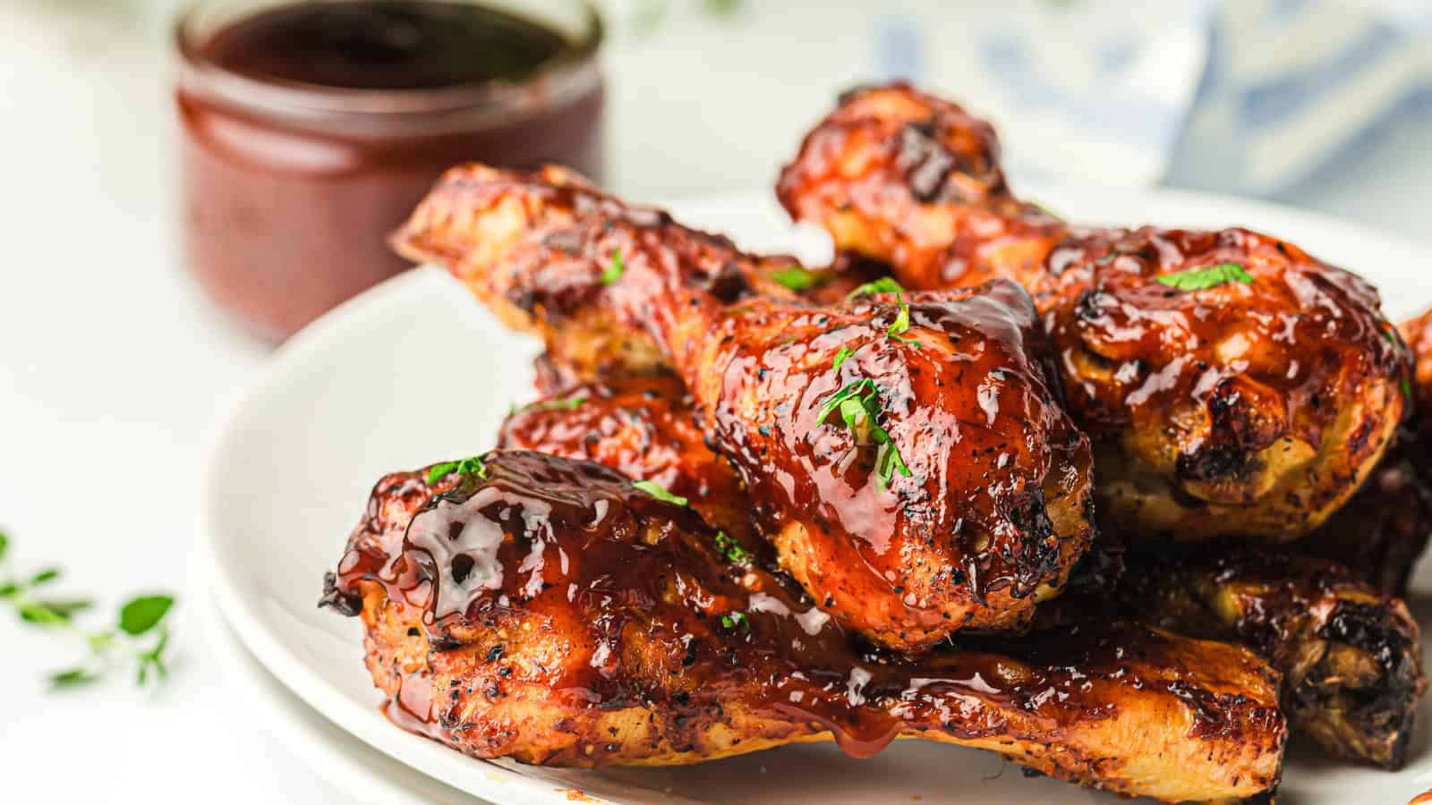 Close-up of a cooked chicken wing with a bite taken, showing juicy and tender meat covered in dark barbecue sauce.