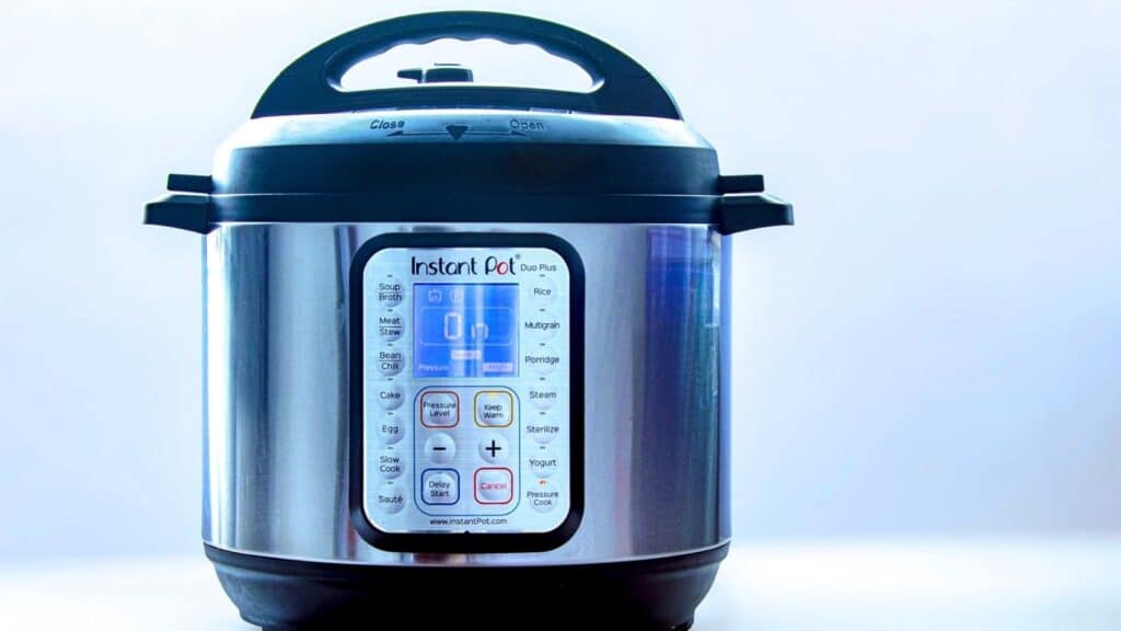 A stainless steel Instant Pot electric pressure cooker with a digital control panel is shown against a plain light background.