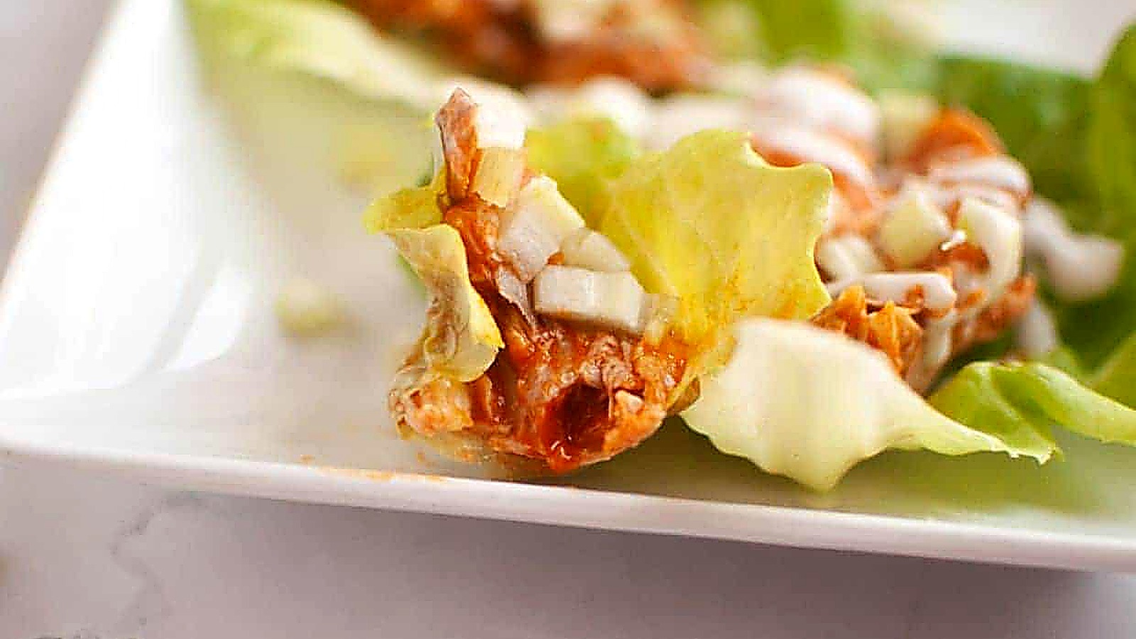 Close-up of a Buffalo Chicken Lettuce Wraps placed on a white plate.