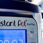 Close-up of an Instant Pot Duo Plus electric pressure cooker and slow cooker, showing its digital display and part of the control panel with buttons for Soup, Broth, and Rice.