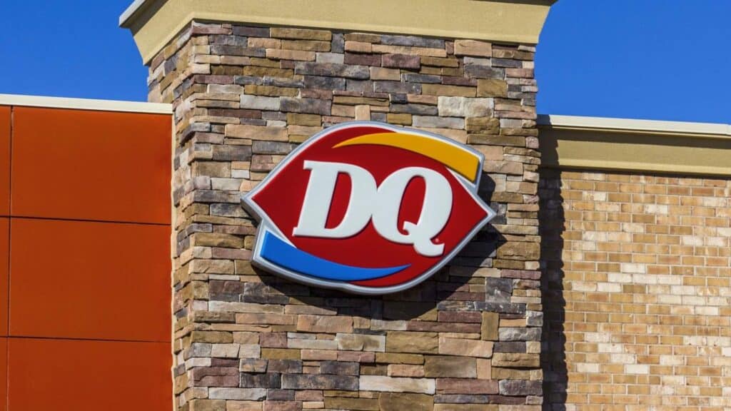 The exterior of a Dairy Queen restaurant with the red and blue "DQ" logo mounted on a brick wall.