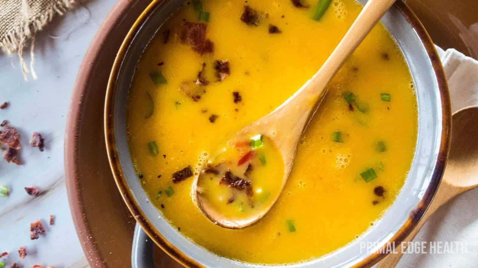 Beer cheese soup with wooden spoon in a bowl.