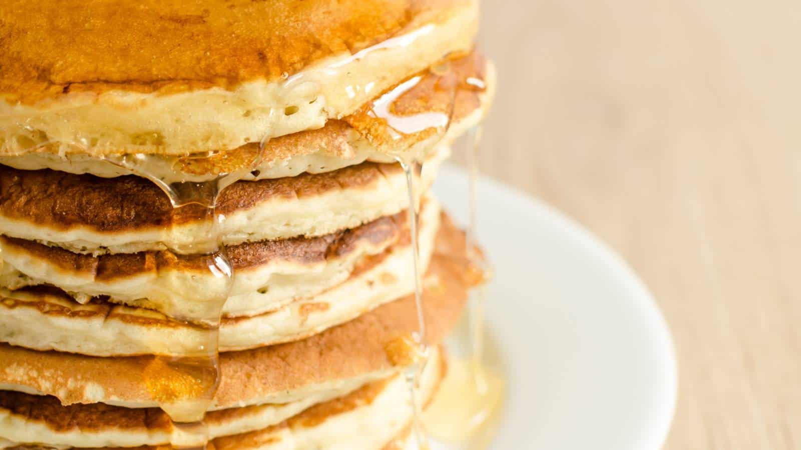 A stack of McDonald&rsquo;s Pancake Recipe with syrup drizzling down.