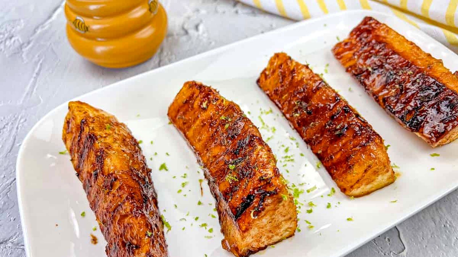 Four pieces of Grilled Pineapple With Buttery Lime Glaze on a white rectangular plate.
