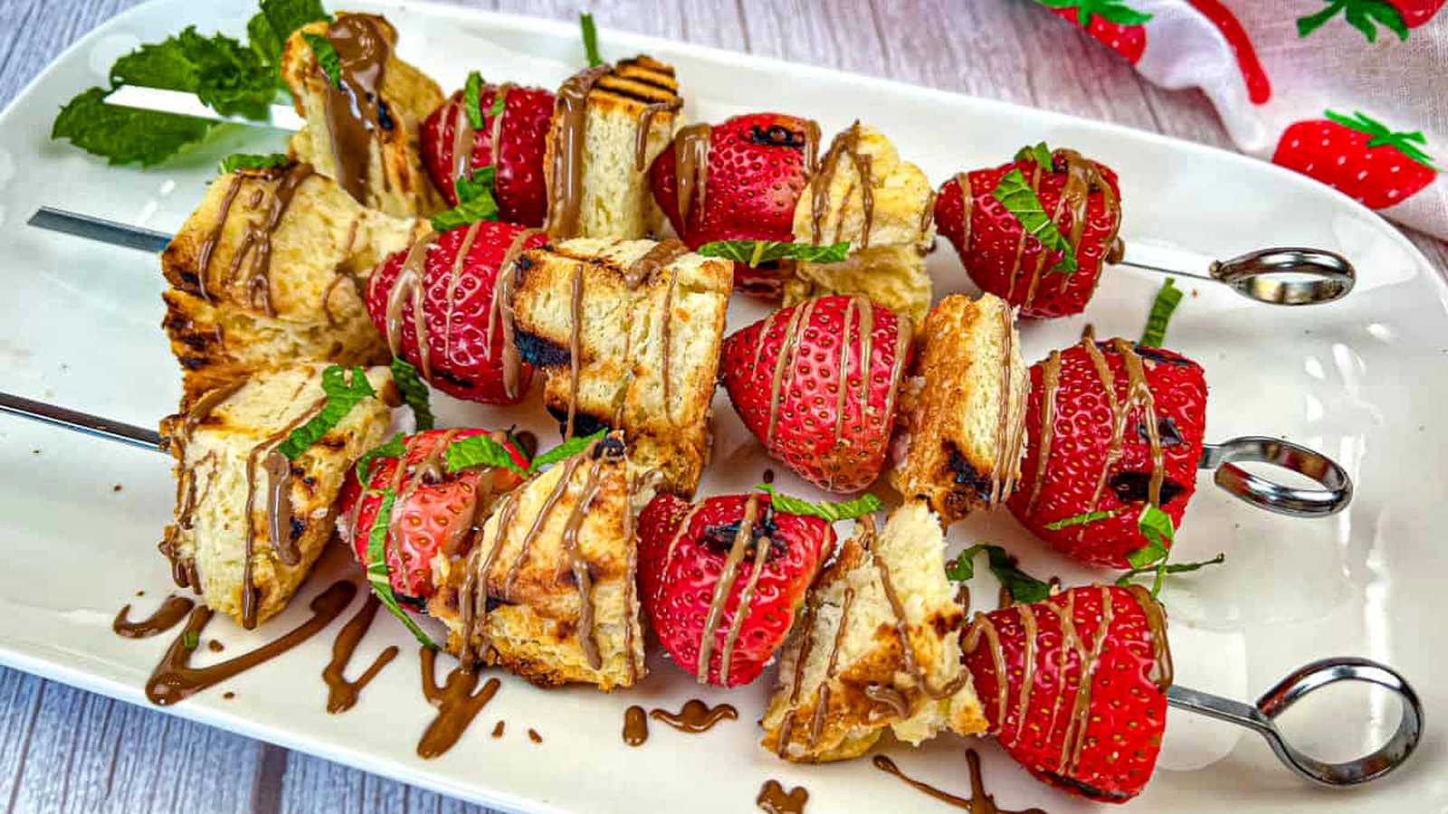 Three pieces of Grilled Strawberry Shortcake Skewers on a white plate.