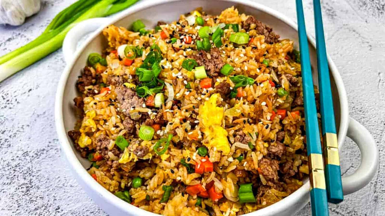 Ground Beef Fried Rice served in a white bowl with blue chopstick on top.