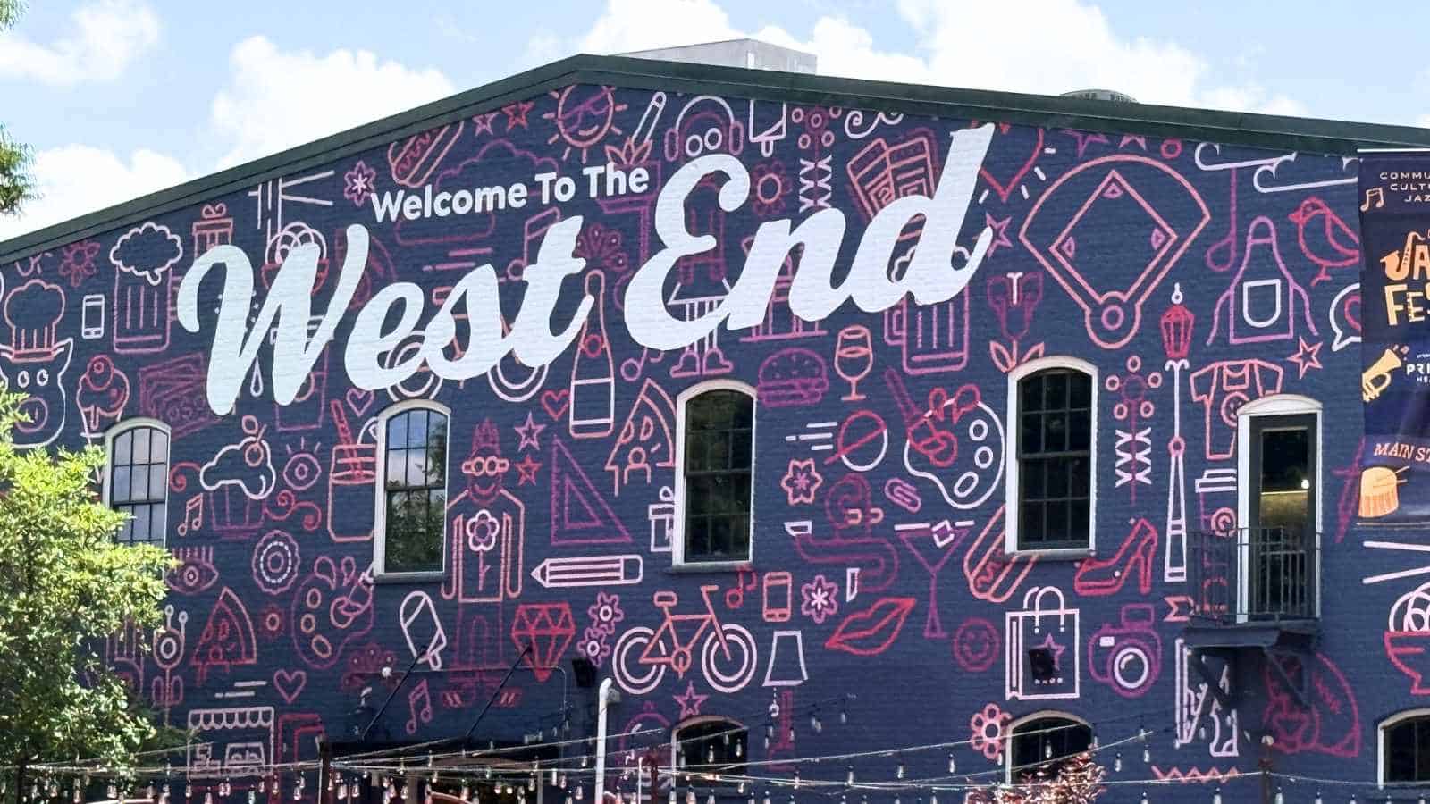 A large mural on a building reads "Welcome To The West End" with various outlined icons and a dark purple background.