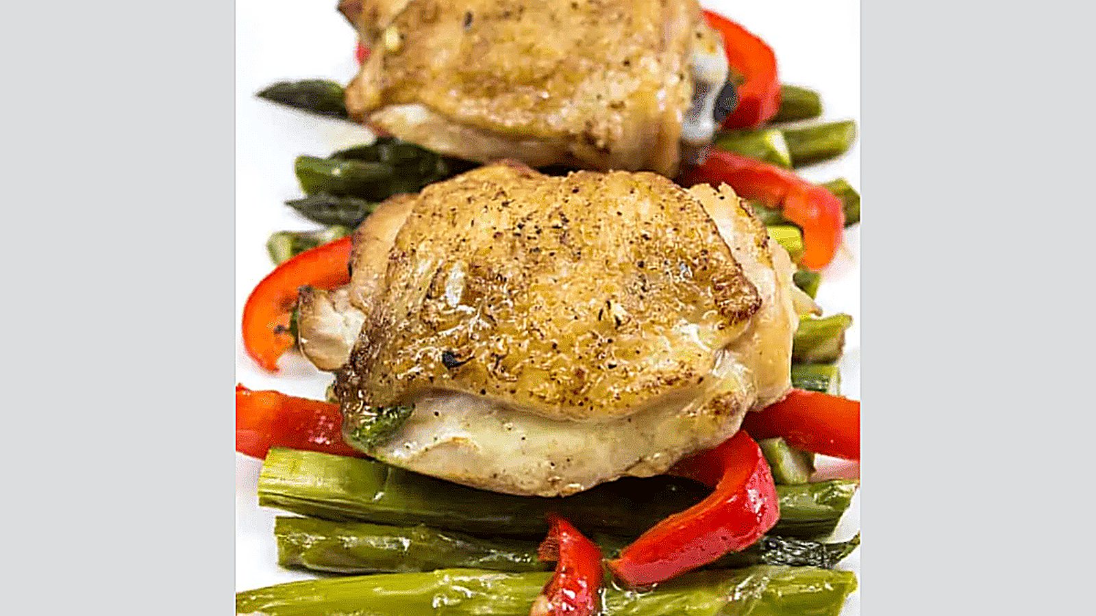 Garlic Chicken Skillet with peppers and asparagus on a white plate.