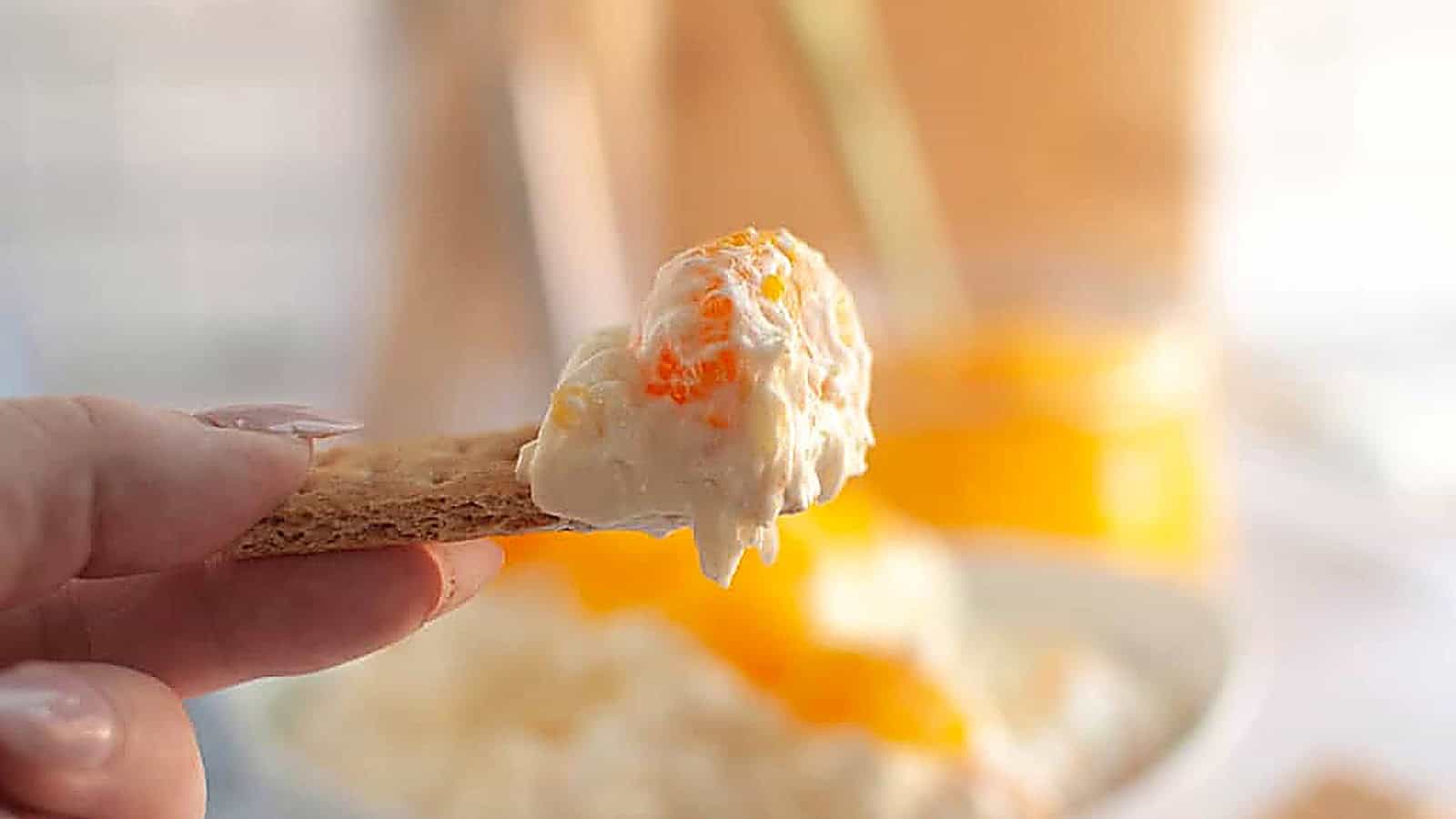 Overhead shot of a white bowl filled with creamy Orange Fluff Salad, topped with mandarin oranges and served with graham crackers.