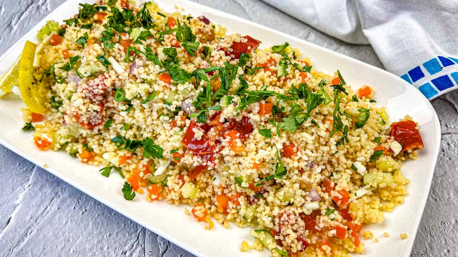 A plate of Mediterranean Couscous Salad With Smoked Tomatoes topped with parsley.