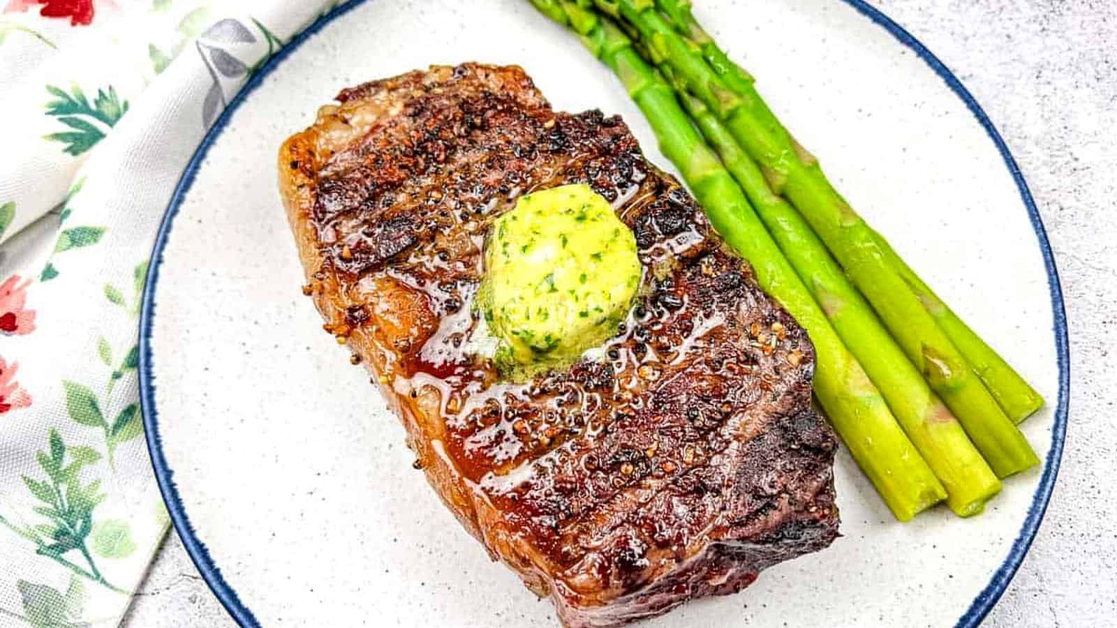 Reverse Seared Smoked Steaks with Smoked Garlic Butter on a plate with asparagus.