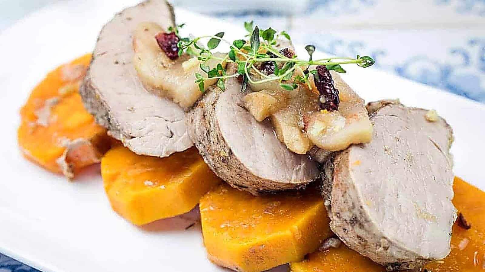 A serving of Slow Cooker Pork Tenderloin with Sweet Potatoes & Apples on a white platter.
