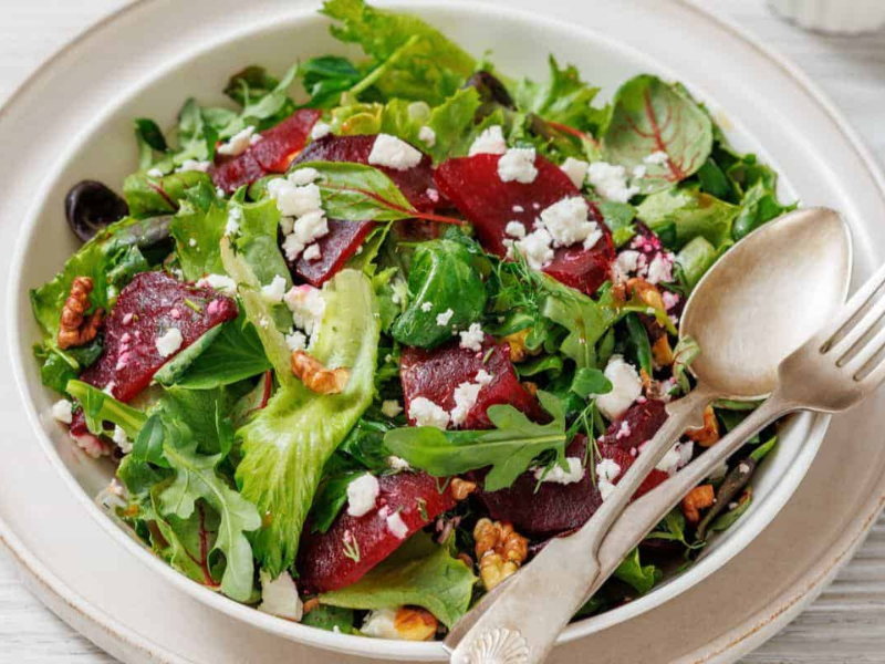 A plate of Beet Salad with Goat Cheese & Walnuts, served with a fork and spoon on the side.