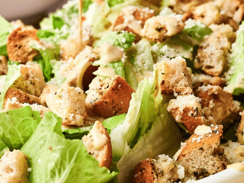 A Caesar salad with romaine lettuce, croutons, grated cheese, and dressing.