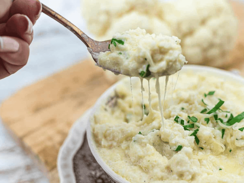 Cheesy Cauliflower Rice on a spoon with melted cheese strikes.
