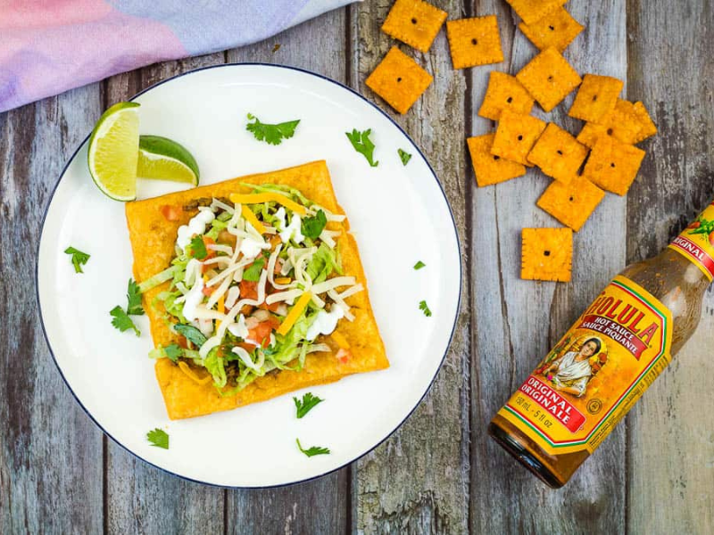 Cheez-It Tostada on a plate with hot sauce in a bottle.