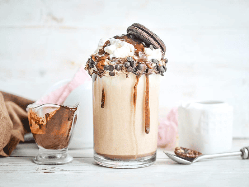 Cookie Dough Milkshake with a spoon and syrup in the background.