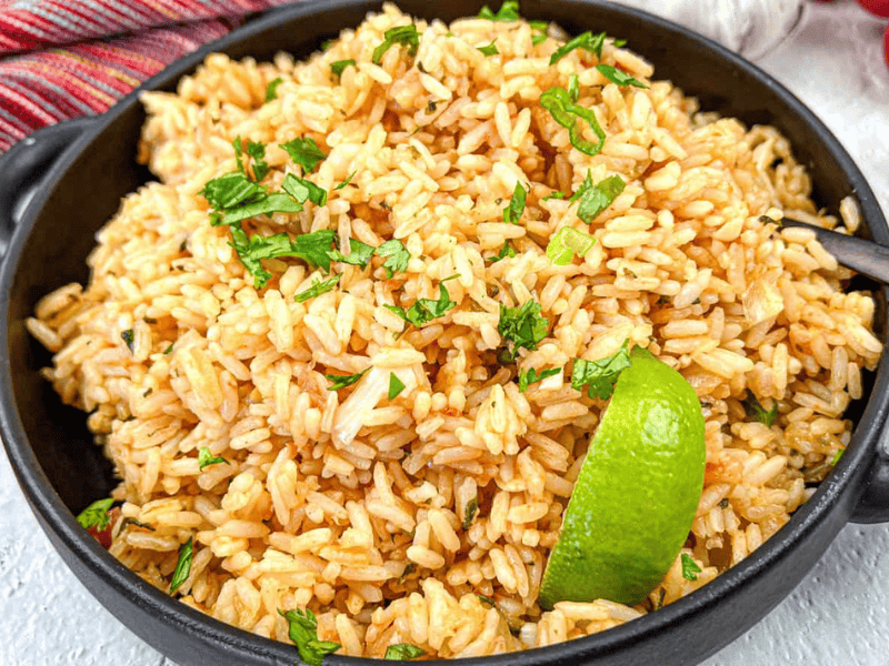 Mexican Rice with a slice of lime on a black bowl.