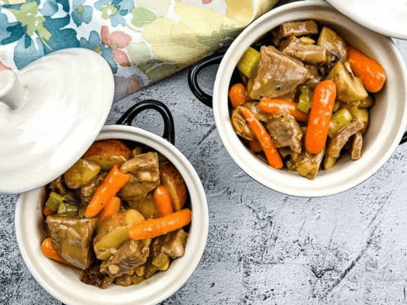 Two bowls of leftover roast beef stew on a table.
