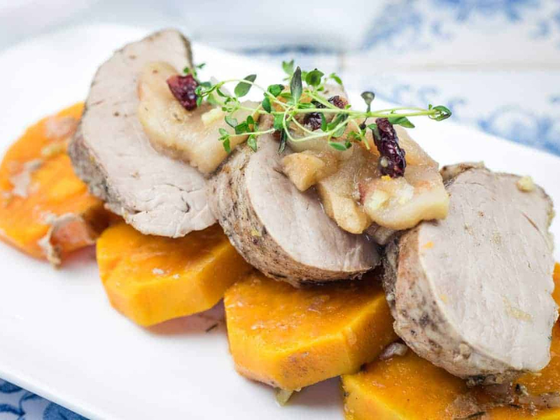 A serving of Slow Cooker Pork Tenderloin with Sweet Potatoes & Apples on a white platter.