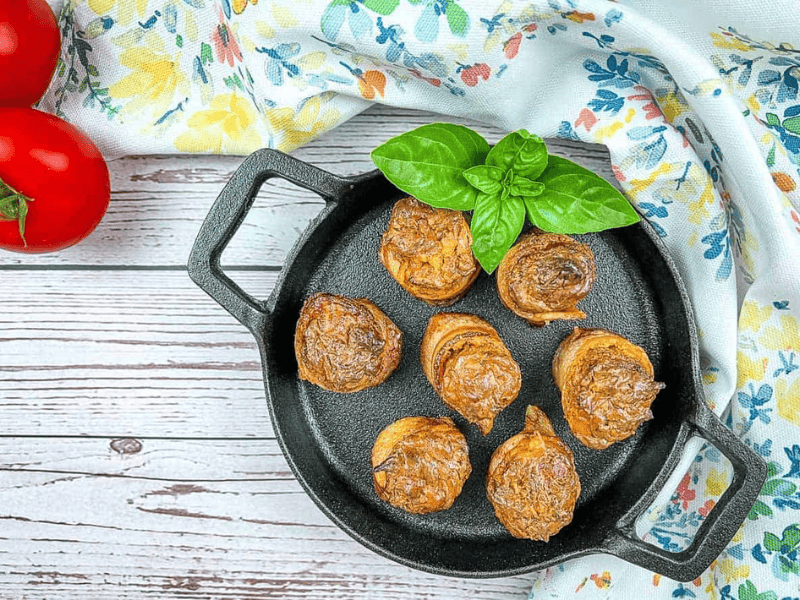 Smoked pork shots in a skillet with basil and tomatoes.
