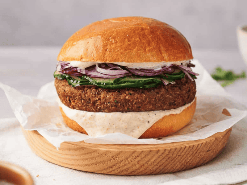 A homemade veggie burger in a bun, on a wooden plate, ready to eat.