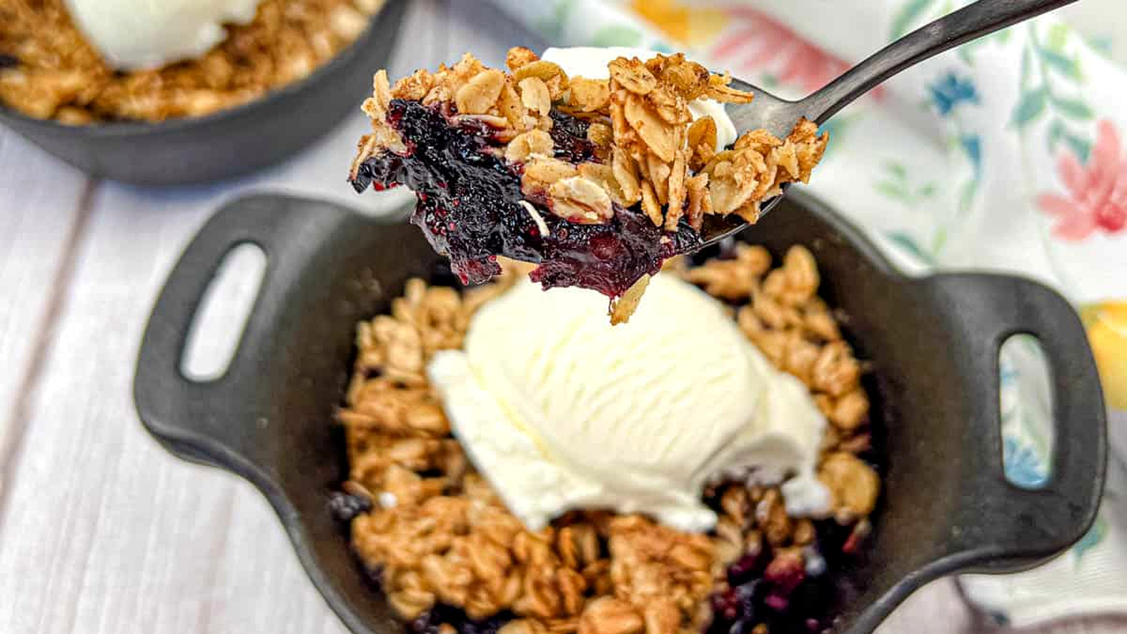 A spoon lifts a portion of Smoked Berry Crisp from a bowl.