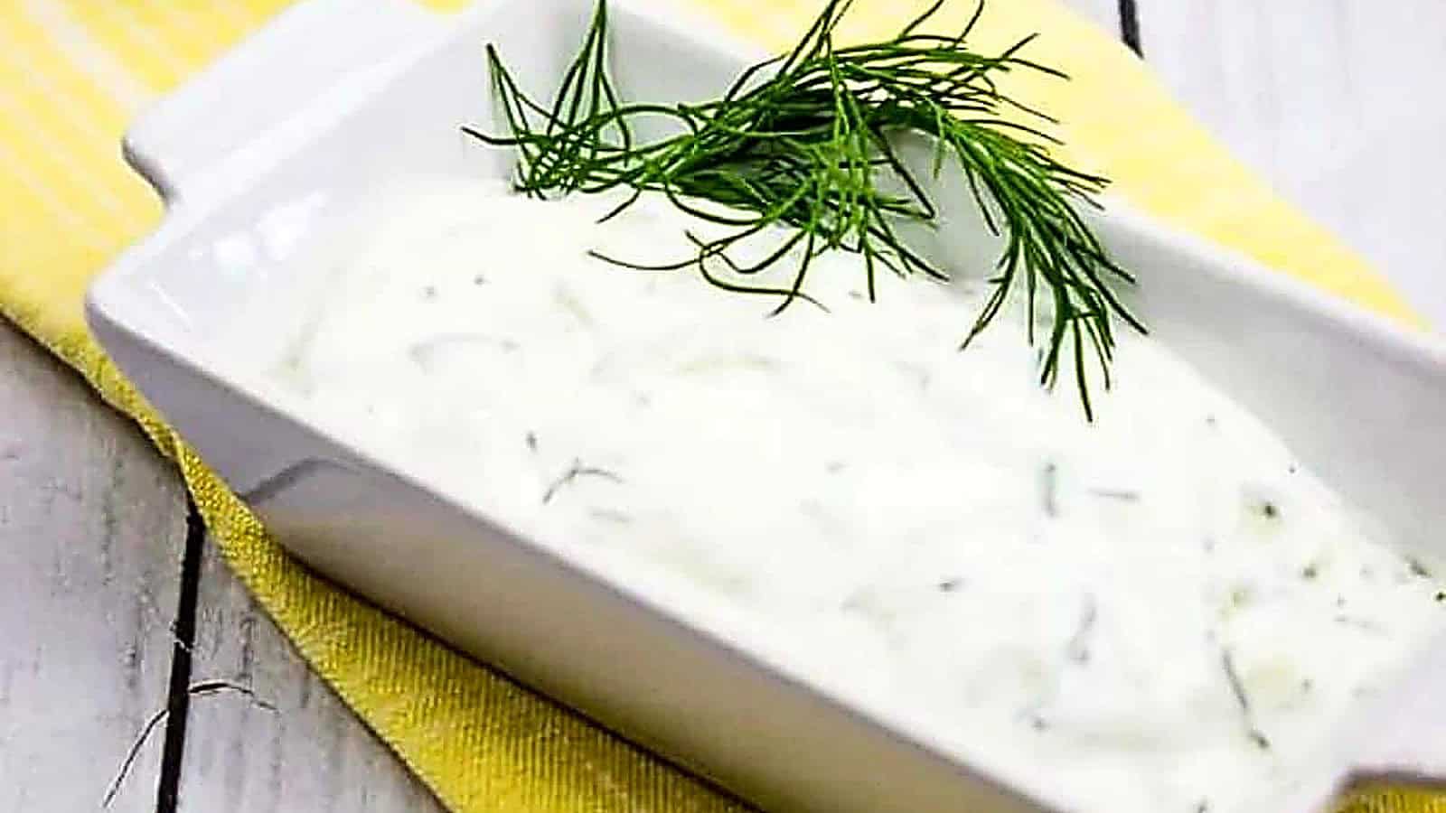 A bowl of dill dip with a sprig of dill.