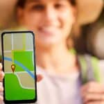 A person participates in a scavenger hunt, holding a smartphone displaying a digital map with a red location pin. The person's face is blurred, and the outdoors background is out of focus.