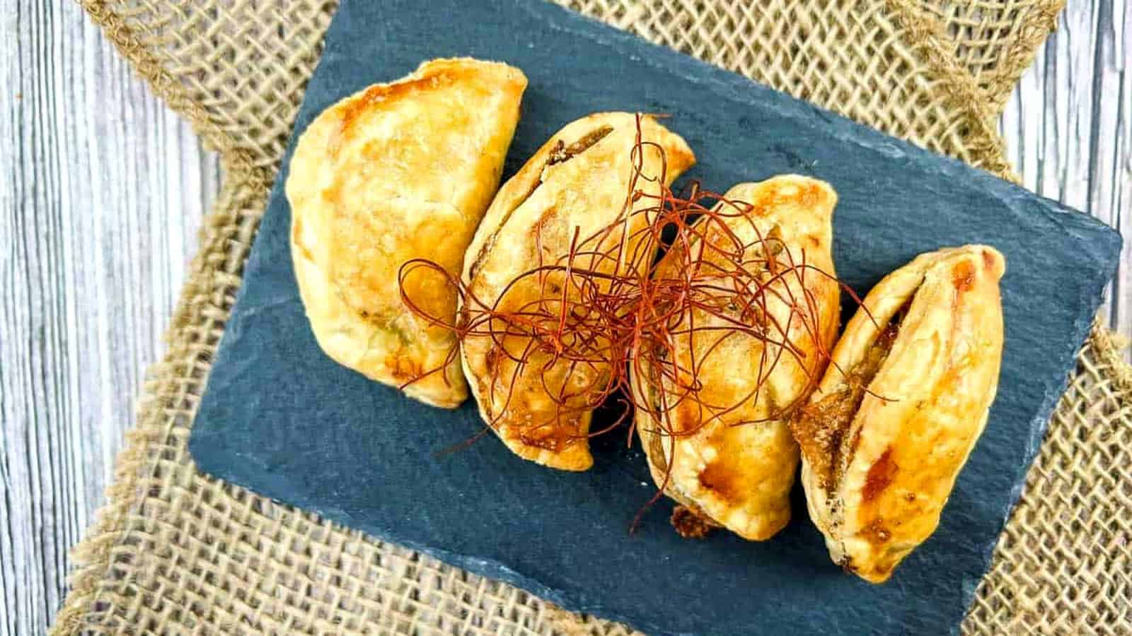 Four pieces of Air Fryer Beef Empanadas on a black rectangular slate.