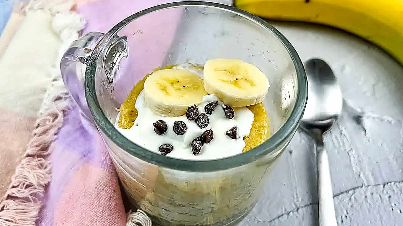 Banana chocolate mug cake with spoon and banana.