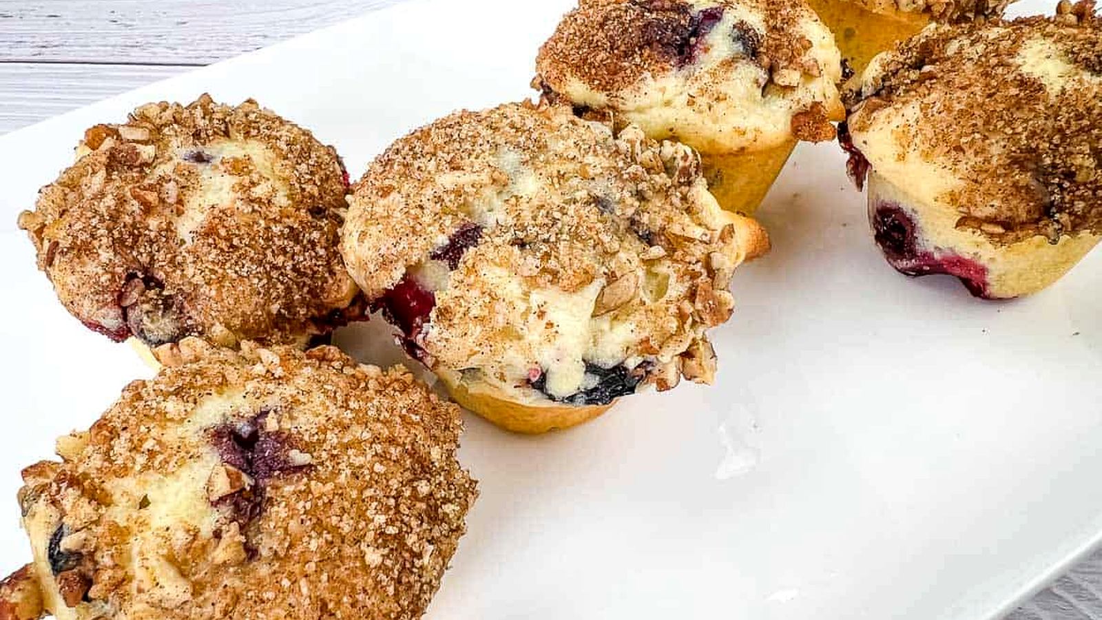 Blueberry crumb muffins on a white plate.