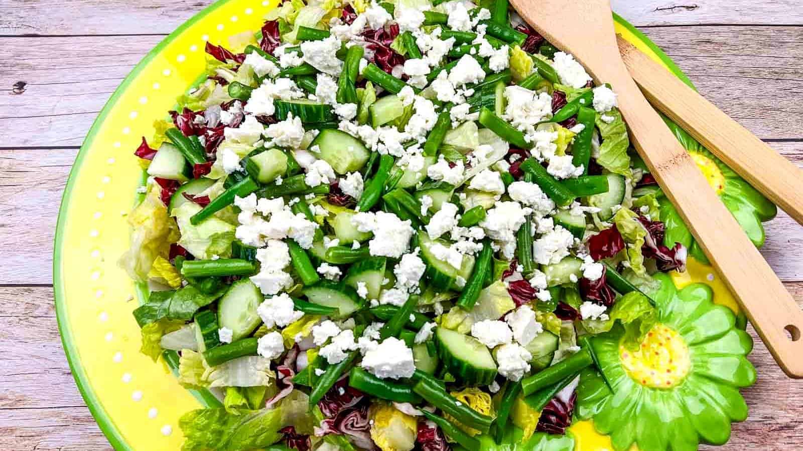 Mediterranean Chopped Salad with crumbled feta cheese, on a yellow plate with flower designs.