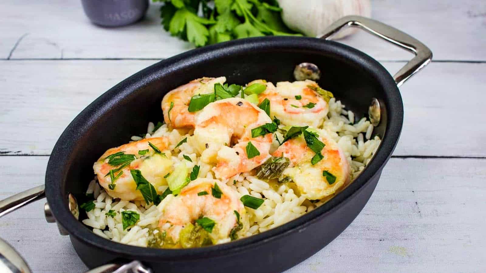 Garlic Shrimp Scampi on a bed of rice in a black oval dish.