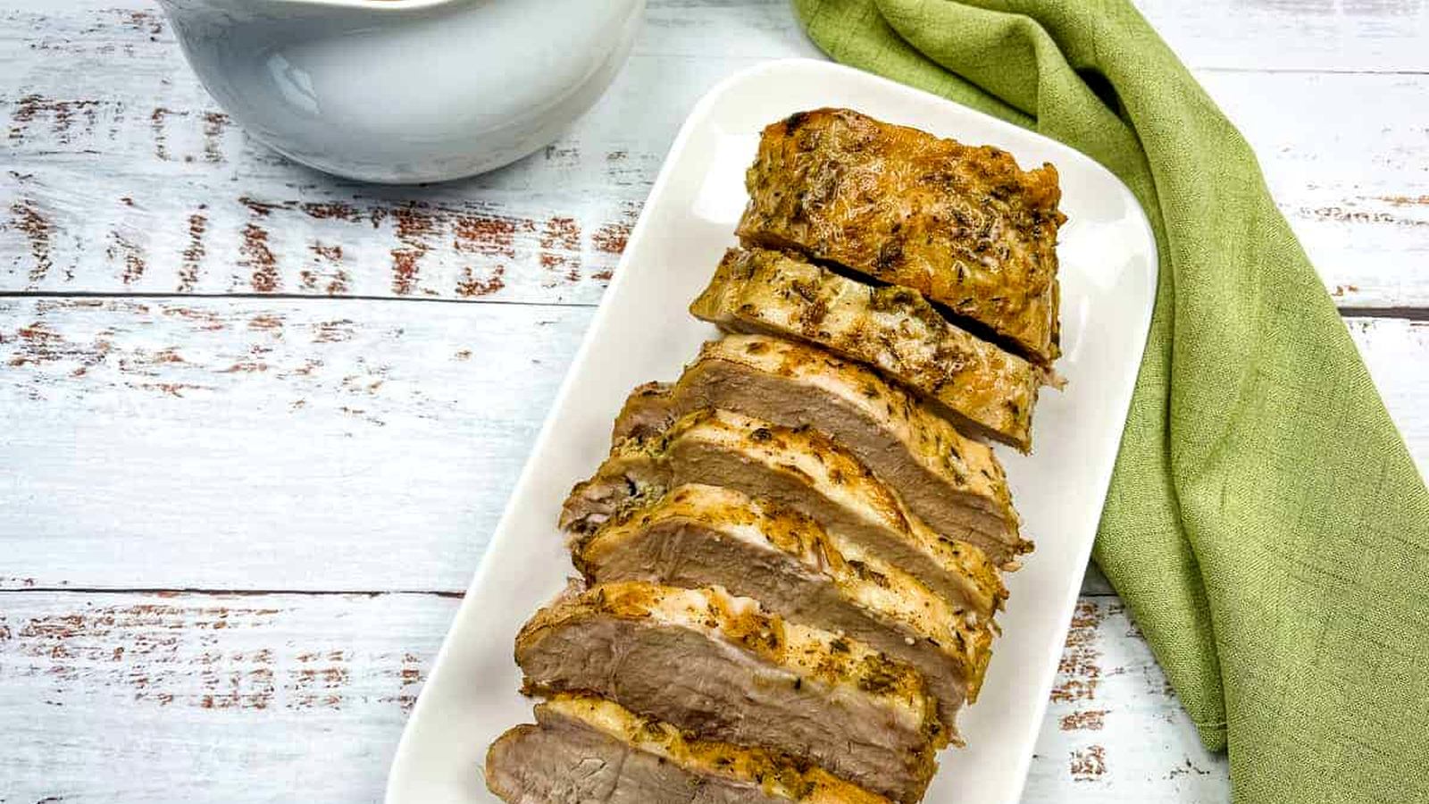 German Pork Loin on a platter with a gravy boat nearby.