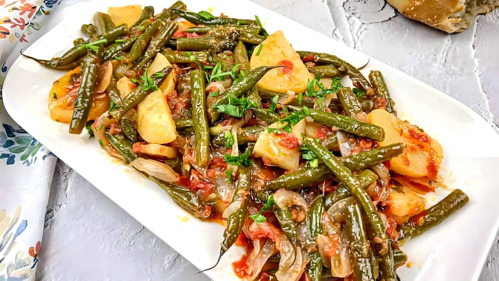 Greek Green Beans served on a white rectangular plate.