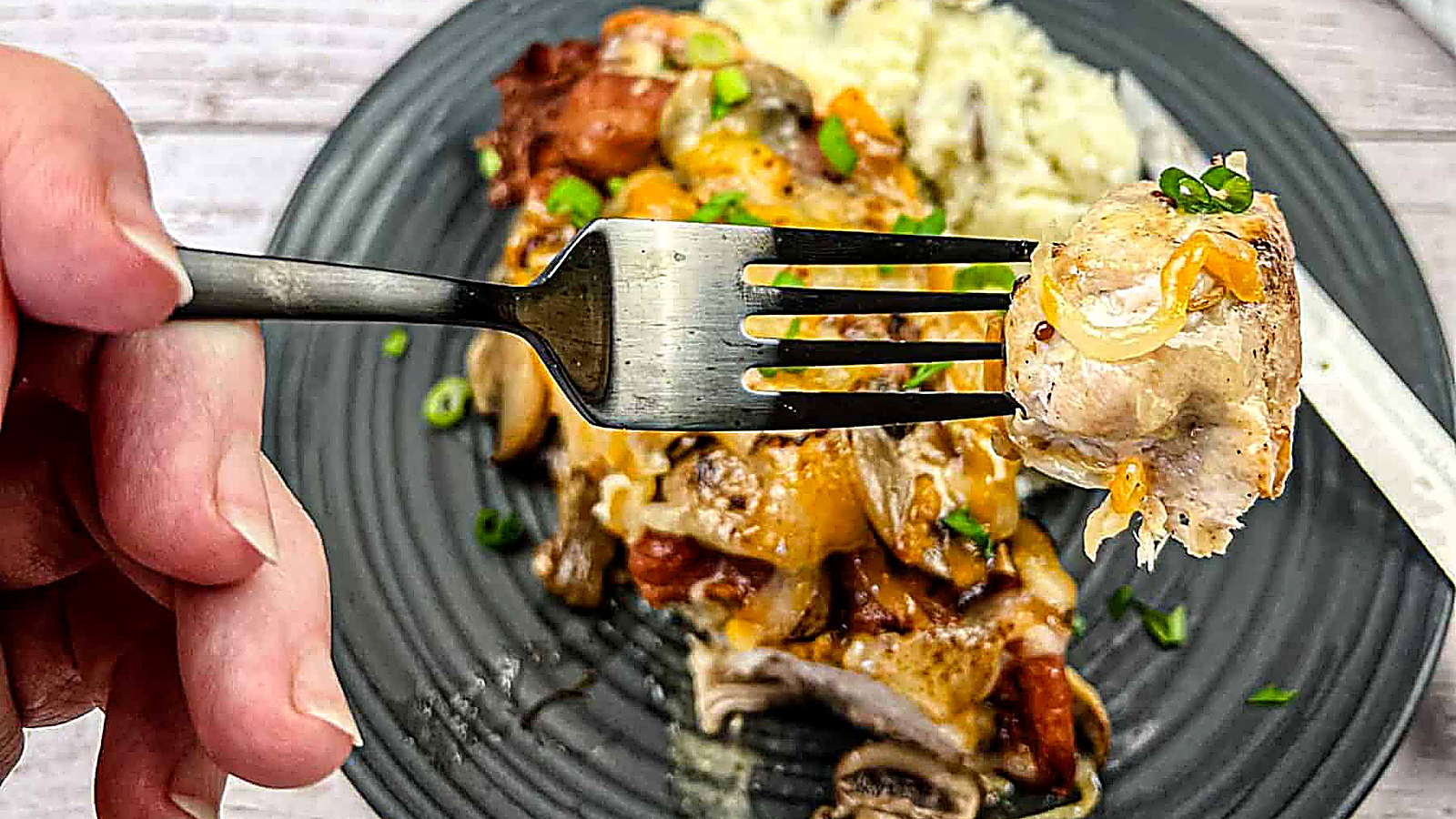 Close-up of a hand holding a fork with a bite of copycat Alice spring chicken.