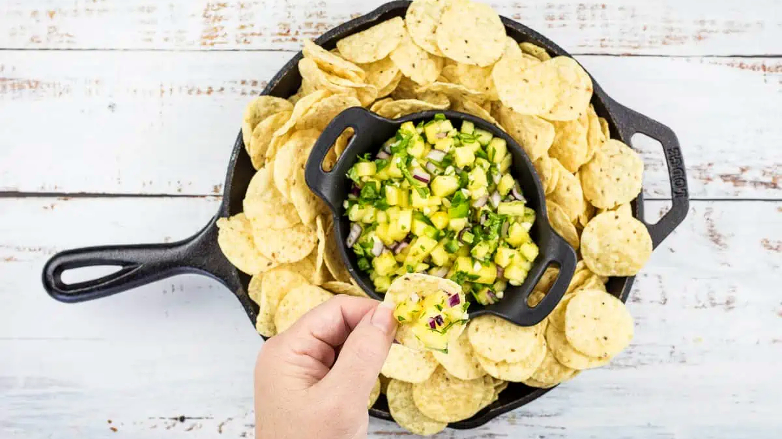 Pineapple salsa in a skillet with tortilla chips.